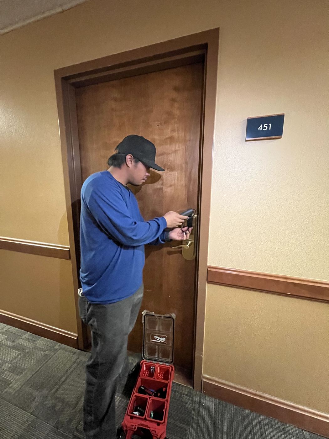 Technician programming a SALTO smart lock on a lodge unit door with a portable programming device