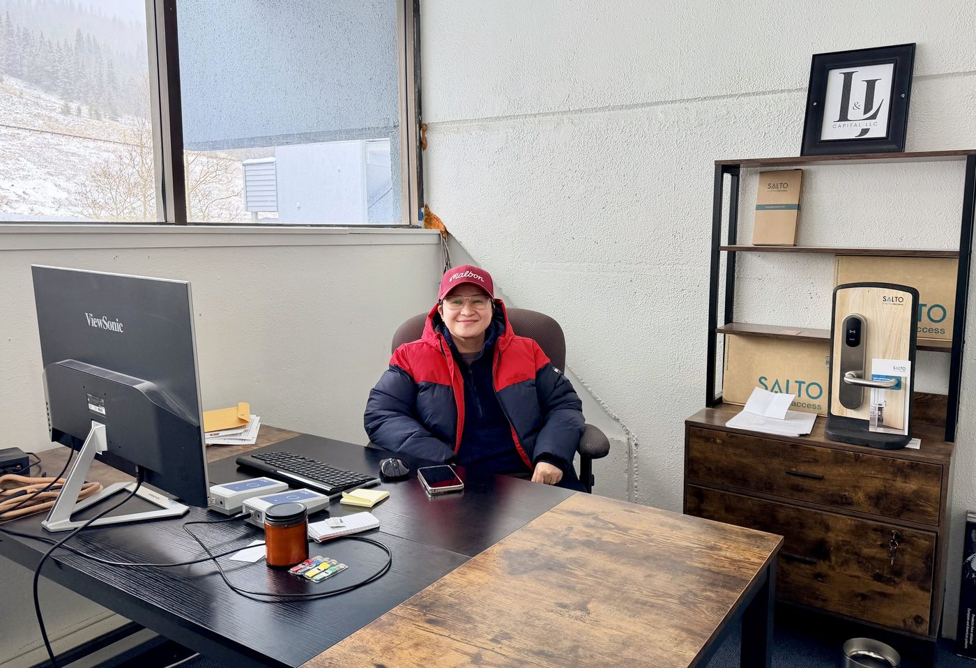 Lynn B. Salvacion at her desk, with SALTO hardware on the shelf behind her